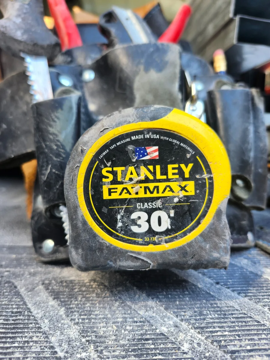 A heavily used STANLEY FATMAX 30-foot tape measure from a carpenter tool pouch.