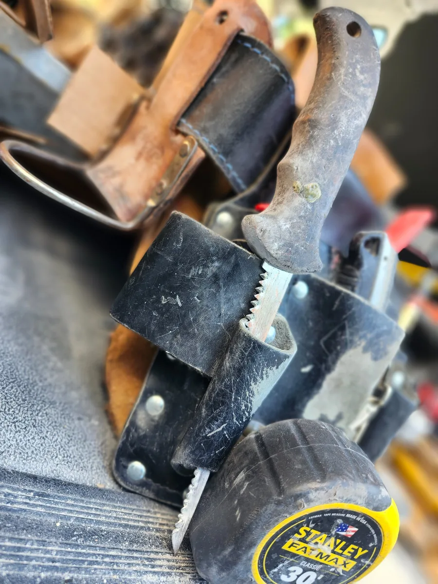 A field-used Shark Rockeater drywall saw in a carpenter tool pouch.