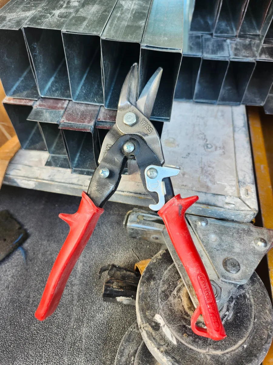 A field-used pair of Crescent Wiss aviation snips resting against metal framing material.